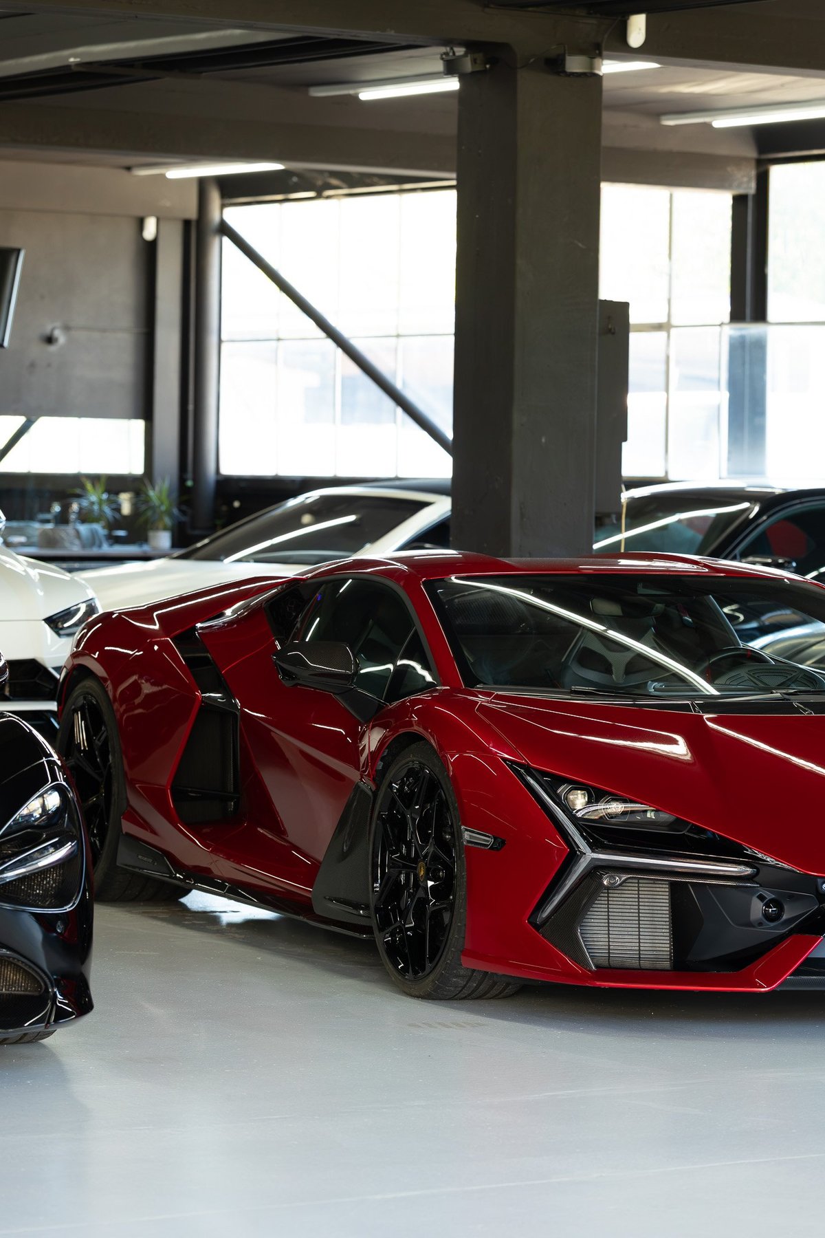 Red sports car with open door in a modern garage with concrete columns — automotive content production